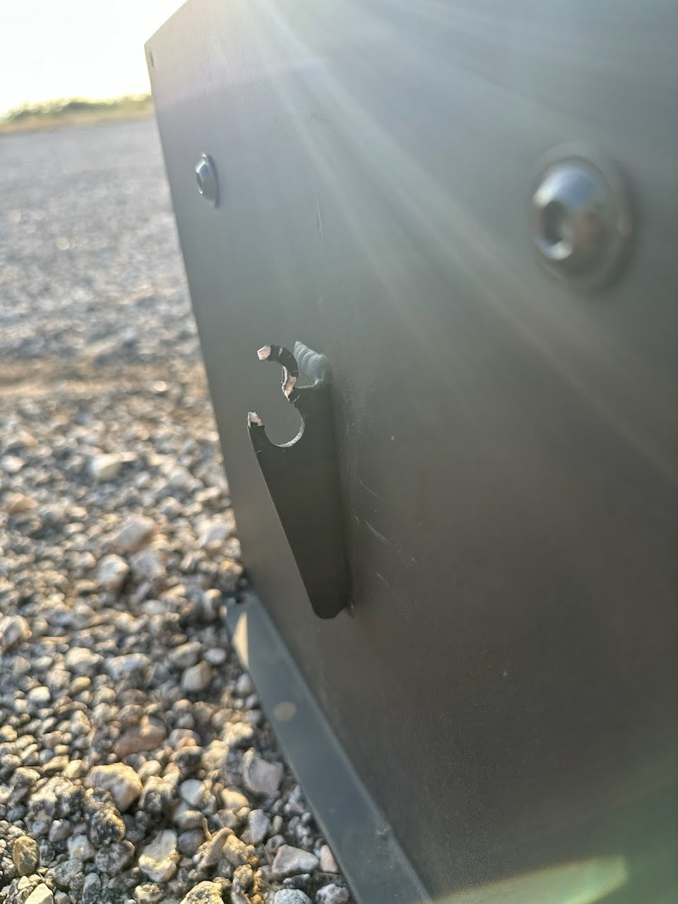 The failed lift point bracket, showing the material torn out between the hole and the free edge.